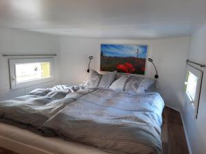 Tiny Haus am Motzener See في Motzen: غرفة نوم بسرير مع لوحة على الحائط