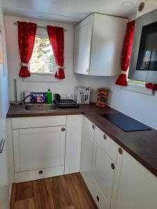 a small kitchen with white cabinets and a sink at Tiny Haus am Motzener See in Motzen