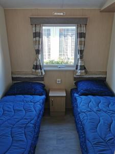 two beds in a small room with a window at CS 71 - Vakantiepark Callassande in Callantsoog