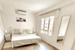 a white bedroom with a bed and a mirror at Apartamento con Playa del Arenal a los pies in Platja de l'Arenal