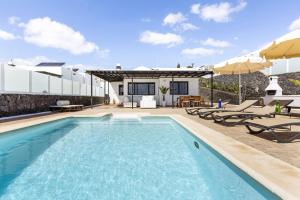 a swimming pool with chairs and a house at Villa 22 in Puerto del Carmen