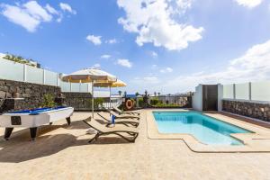 a pool with a ping pong table and chairs and an umbrella at Villa 22 in Puerto del Carmen