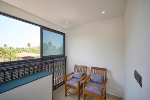2 Stühle auf einem Balkon mit einem großen Fenster in der Unterkunft Venice Iva Residency in Alappuzha