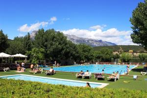 una gran piscina con gente sentada a su alrededor en Bungalows Peña Montañesa en Aínsa
