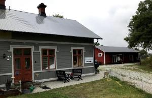 a gray house with a red building in the background at Tågmagasinet Fidenäs in Burgsvik