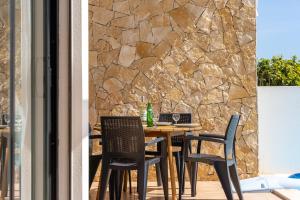 a table and chairs on a patio with a stone wall at Villa Hobie Cat in Sagres