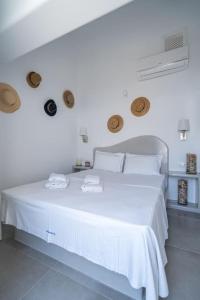 a white bedroom with a large white bed with two towels at Acrus Villa Santorini with Heated pool in Karterados