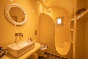 a bathroom with a sink and a toilet and a mirror at Acrus Villa Santorini with Heated pool in Karterados