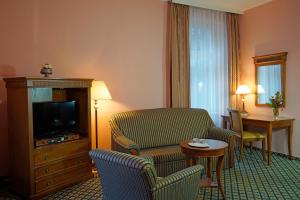 カルロヴィ・ヴァリにあるHotel Villa Laurettaのテレビとリビングルームが備わるホテルルームです。