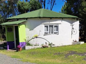 una pequeña casa blanca con techo verde en Purple House B&B Smithfield en Smithfield