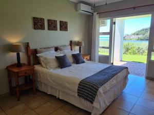 Schlafzimmer mit einem Bett und Blick auf das Wasser in der Unterkunft Villa Arroyo, Estuary Estate, Port Edward in Port Edward