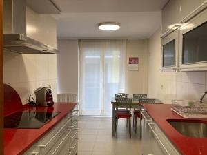 a kitchen with red counter tops and a table with chairs at Turismo rural, San Sebastián,playa, parking privado in Azpeitia