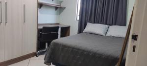 um quarto com uma cama, uma secretária e uma cadeira em Aconchego em Chapecó