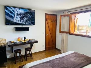 a bedroom with a bed and a table with a television at Suítes Andorinhas in Monte Verde