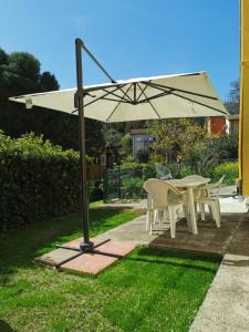 a table and chairs under an umbrella in a yard at N194 - Numana, ampio trilocale con giardino in Numana