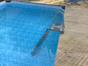 a swimming pool with a handrail in a blue swimming pool at Le Petite Barn in Vautorte