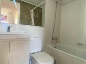 Un baño blanco con inodoro y lavabo. en departamento nuevo amoblado sin uso, en Viña del Mar