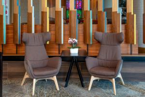 two chairs and a table with a vase of flowers at Grand Bay Hotel San Francisco in Redwood City