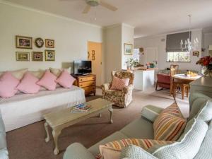 a living room with a couch with pink pillows at Rose Cottage in Knysna