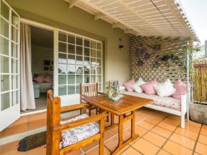 a porch with a wooden table and a couch at Rose Cottage in Knysna
