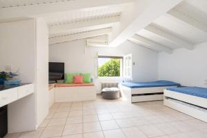 een witte kamer met 2 bedden en een televisie bij Luxurious villa, with big garden next to beach in Selianitika