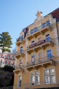 a tall yellow building with a sign on it at Hotel Villa Lauretta in Karlovy Vary