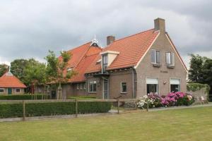 a house with an orange roof and a yard at Ballumerhoeve Petit lodge in Ballum