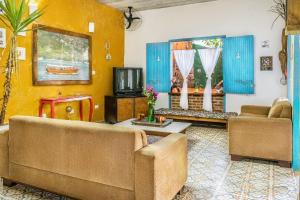 a living room with two couches and a tv at Vilarejo do Perequê in Ilhabela