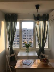 una mesa de comedor con un jarrón de flores y una ventana en Studio Lotus, en Bucarest