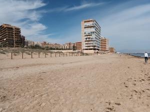 a person walking on the beach with buildings in the background at Duplex junto a la playa in Arenales del Sol