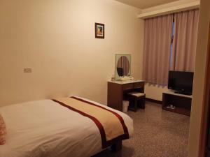 a hotel room with a bed and a television at Mu Xi Ocean View B&B in Beigan