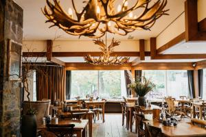 a restaurant with wooden tables and chairs and a chandelier at Badhotel Rockanje in Rockanje