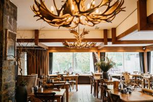 un restaurant avec des tables et des chaises en bois et un lustre dans l'établissement Badhotel Rockanje, à Rockanje