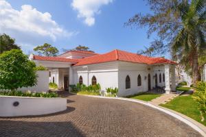 a white house with a red roof and a driveway at The Yellow House, Goa - IHCL SeleQtions in Anjuna