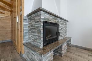 einen gemauerten Kamin mit einem TV darüber. in der Unterkunft Widokowe Domki Gawlaki in Zakopane
