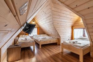 a attic room with two beds and a tv at Widokowe Domki Gawlaki in Zakopane