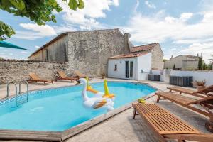una piscina con dos cisnes en una casa en La Maison du Puits, son gîte, et sa piscine, en Villeneuve-la-Comtesse