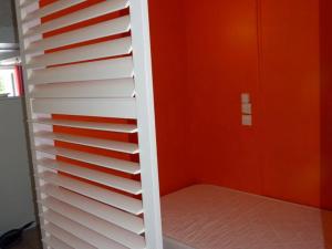 une étagère blanche dans une chambre avec un mur orange dans l'établissement Appartement Le Palais, 2 pièces, 4 personnes - FR-1-418-68, au Palais