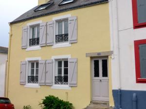 ル・パレにあるAppartement Le Palais, 2 pièces, 4 personnes - FR-1-418-68の白い窓と白いシャッターのある黄色い家