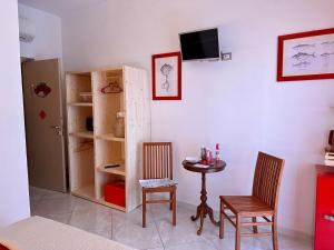 レ・グラツィエにあるCasa del Palombaroのテーブル、椅子2脚、テレビが備わる客室です。