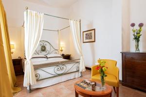 a bedroom with a canopy bed and a yellow chair at Fattoria La Principina Hotel & Congress in Principina Terra