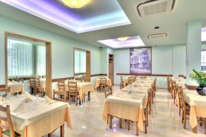 a dining room with white tables and chairs at Hotel Vallechiara in Cesenatico