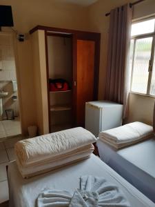 a room with two beds and a refrigerator and a window at Hotel Faisca in Mariana