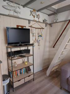 a living room with a television and a staircase at Zomerhuis Tuls in Egmond aan Zee