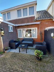 a patio with couches and a table in front of a house at Zomerhuis Tuls in Egmond aan Zee
