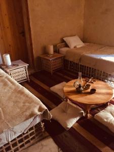 錫瓦的住宿－Tanirt ecolodge，客房设有两张床和一张木桌。