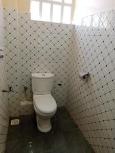 a bathroom with a toilet in a white tiled wall at Denverwing Homes in Eldoret