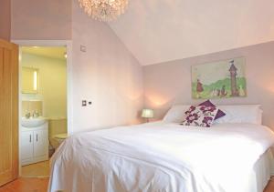 a bedroom with a large white bed with a chandelier at Coach House in Gosport