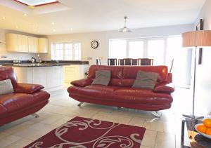 a living room with a red couch and a kitchen at Coach House in Gosport