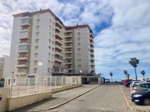 聖瑪麗亞港的住宿－APARTAMENTO VALDEMAR PLAYA - WiFi & Aparcamiento，一座高大的白色建筑,汽车停在停车场